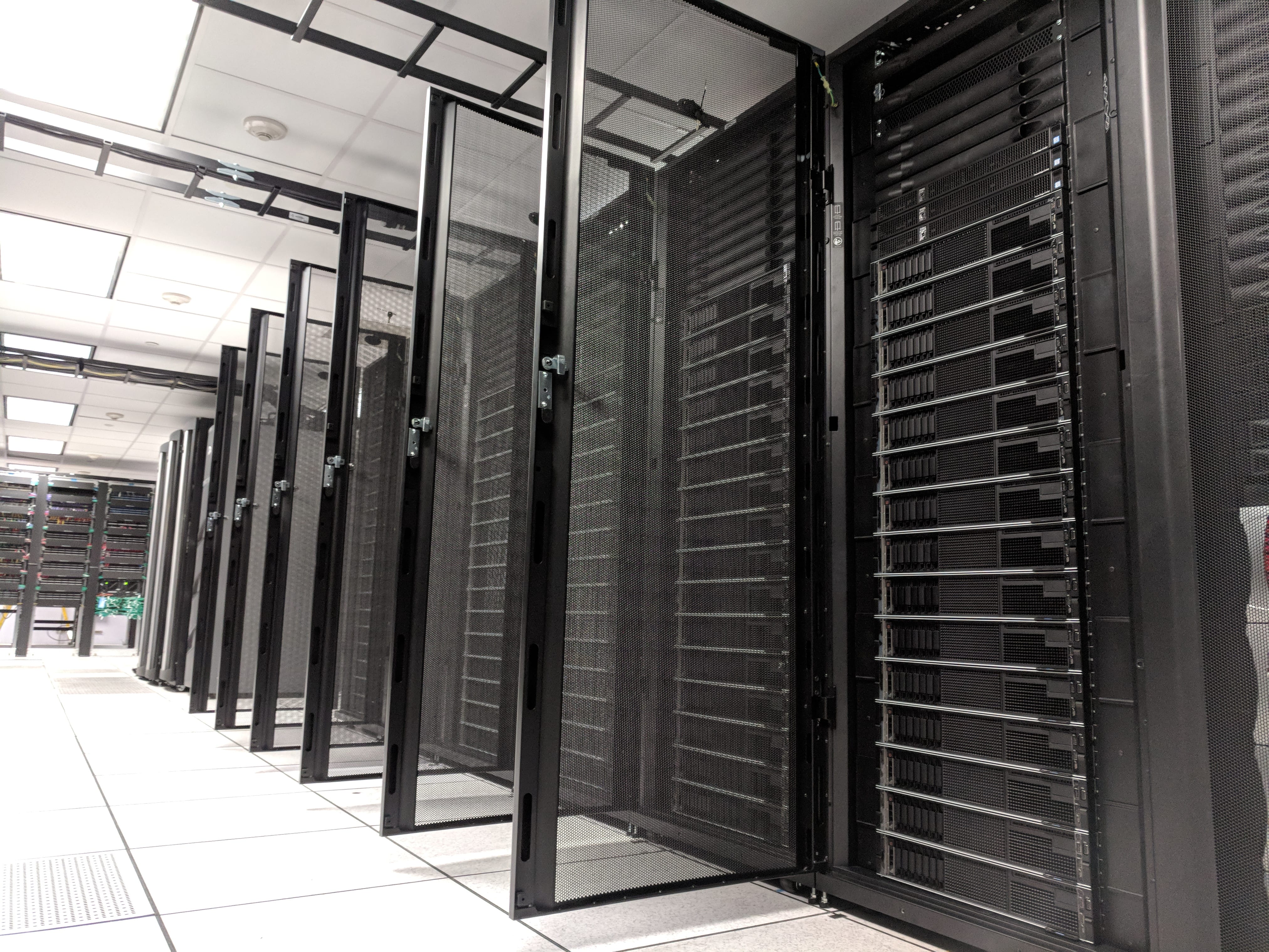 Ground level view of server racks with doors open showing servers in a row